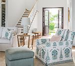 Living room with light-colored walls, furniture, a stairway, and an open doorway to the outside.