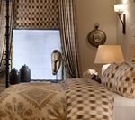 Bedroom interior with patterned bedding, curtains, and a window.