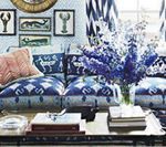 Blue and white living room with patterned sofa, flowers, and framed art.
