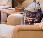 Beige sofa with patterned pillow and wooden table.