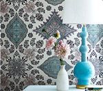 Wallpaper with intricate blue and gray floral patterns, beside a blue lamp and flowers.
