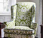 Wingback chair with green and white patterned upholstery, dark trim.
