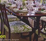 Dining room table set for a meal. Dark wood chairs with patterned seats surround the table. Dishes and glasses are set.