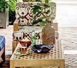 Outdoor seating area with patterned cushions, a wooden coffee table, and drinks.