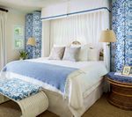Bedroom with blue and white patterned accents, canopy bed, bench, and side table.