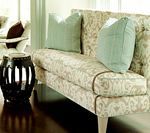 Tufted beige loveseat with light blue pillows, next to a black decorative lantern.