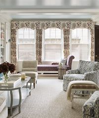 Living room with patterned curtains, neutral furniture, and a window seat.