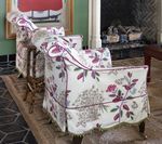 Two floral patterned armchairs in a room with a fireplace and rug.