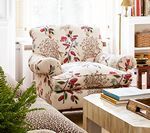 Floral armchair in a living room next to a coffee table with books.