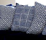 Navy blue and white patterned throw pillows on a dark blue surface.