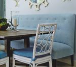 Blue upholstered dining bench with woven white chair. Wooden table.