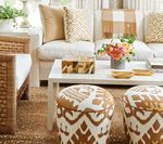 Living room with white sofa, coffee table, patterned ottomans, and tan decor.