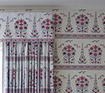 Floral patterned curtain and matching valance next to wallpaper with the same pattern.