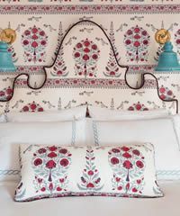 Bed with patterned headboard, matching floral pillows, and blue lamps.