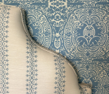 Wallpaper with blue and white damask pattern being peeled back to reveal a striped wallpaper.