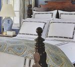 Bedroom with a made bed featuring white bedding, a paisley bedspread, and a wooden bed frame.