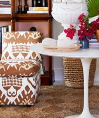 A patterned chair and ottoman sit near a white table with a vase of flowers.