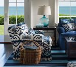 Coastal living room with patterned armchair, blue rug, ocean view.