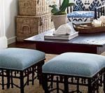 Two blue upholstered ottomans with dark, ornate frames in front of a living room scene.