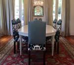 Dining room with oval white table, patterned chairs, and a red rug.