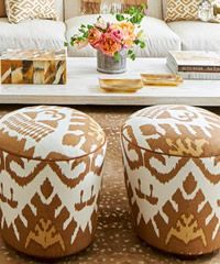 Two patterned ottoman stools in front of a coffee table with a floral arrangement.