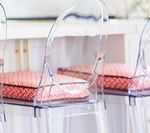 Clear plastic chairs with pink patterned cushions.