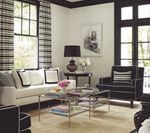 Living room with white sofa, black armchair, and glass coffee table. Black and white curtains and door frames.