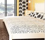 Bedroom with a white bed frame, patterned bedding, and a large window overlooking trees.