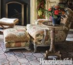 Upholstered chair and ottoman in a living room, with a patterned rug and side table holding flowers.