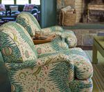 Two armchairs with patterned fabric in a living room, near a fireplace.