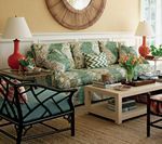 Living room with floral couch, bamboo chair, coffee table, lamps, and mirror.