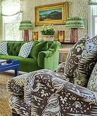 Living room with green sofa, patterned armchair, and lamps.