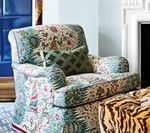 Armchair with patterned fabric and green pillow next to a tiger print ottoman.