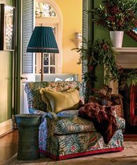 Cozy armchair with patterned fabric, teal lamp, and throw blanket near a fireplace, green wall, and yellow door.