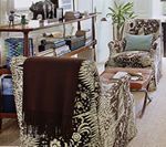 Living room with patterned armchairs, shelves with decor, and a brown blanket.