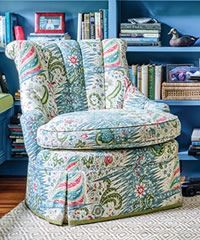Upholstered armchair with floral and paisley pattern, in front of a blue bookcase.