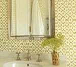Bathroom with patterned wallpaper, mirror, sink, and vase of flowers.
