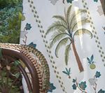 Palm tree print fabric draped over a wicker chair, outdoors.