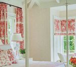 Bedroom with red and white patterned curtains and bedding.