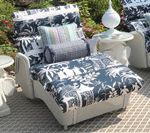 White chaise lounge with black and white tropical pattern cushions and pillows on an outdoor patio.