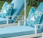 Two blue lounge chairs with white frames and patterned throw pillows outdoors.