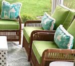 Rattan furniture with lime green cushions and teal pillows on a porch.