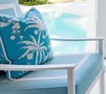 Blue cushion on white chair by a pool.