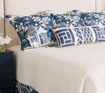 Bed with blue and white patterned pillows and a white comforter.