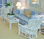 Living room with white wicker furniture, blue patterned couch, and gold accent pillow.
