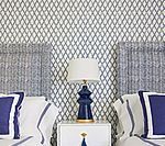 Twin beds with blue and white accents, a nightstand, and a patterned wallpaper background.