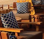 Outdoor seating with wood chairs, tan cushions, and navy pillows with diamond pattern.