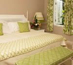 Bedroom with white bed, green accents, and a window with curtains.