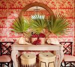 A decorative entryway with a mirror, console table with greenery, and patterned wallpaper.