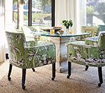 Green patterned chairs around a table in a sunlit room.